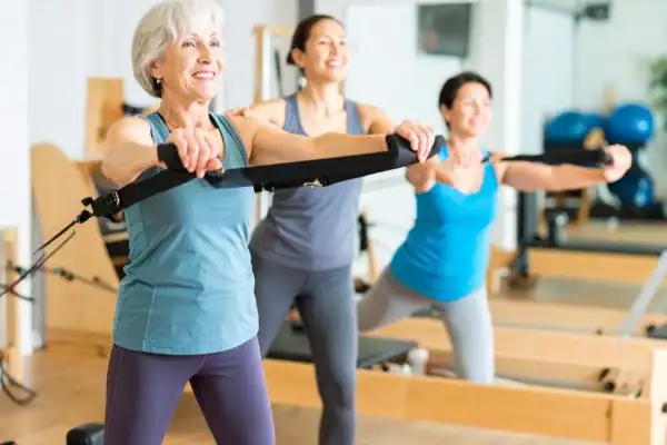 Toning Arms After 60: Empowering Womens Fitness Through Effective Weight Training 2 older woman doing weight training Gloucestershire and resistance in the gym to tone upper arms